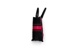 Load image into Gallery viewer, A black knit wristlet bag with a vibrant pink glittery stripe down the center and a matching pink logo on the front, featuring two black wrist loops, shown from a top-down angle on a white background.